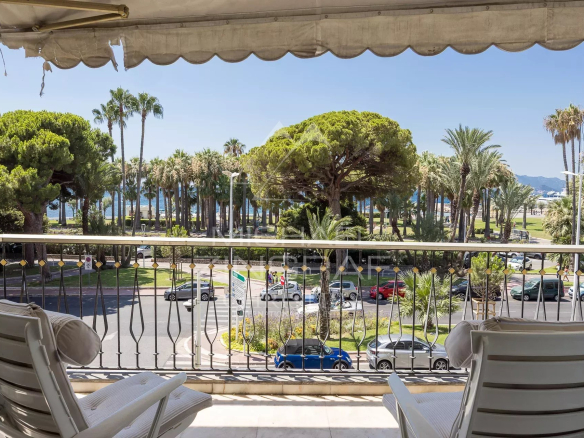Terrasse d'un appartement à Cannes avec vue sur la mer et des palmiers.