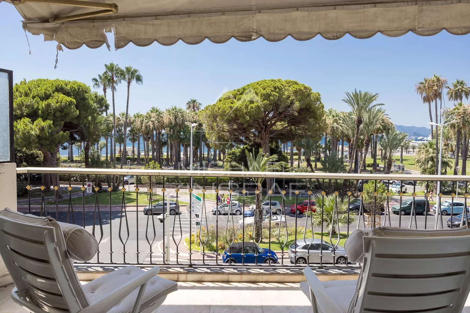 Terrasse avec vue à Cannes Terrasse d'un appartement à Cannes avec vue sur la mer et des palmiers.