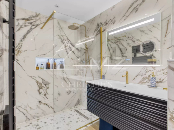 Salle de bain moderne avec douche en verre et décor en marbre.