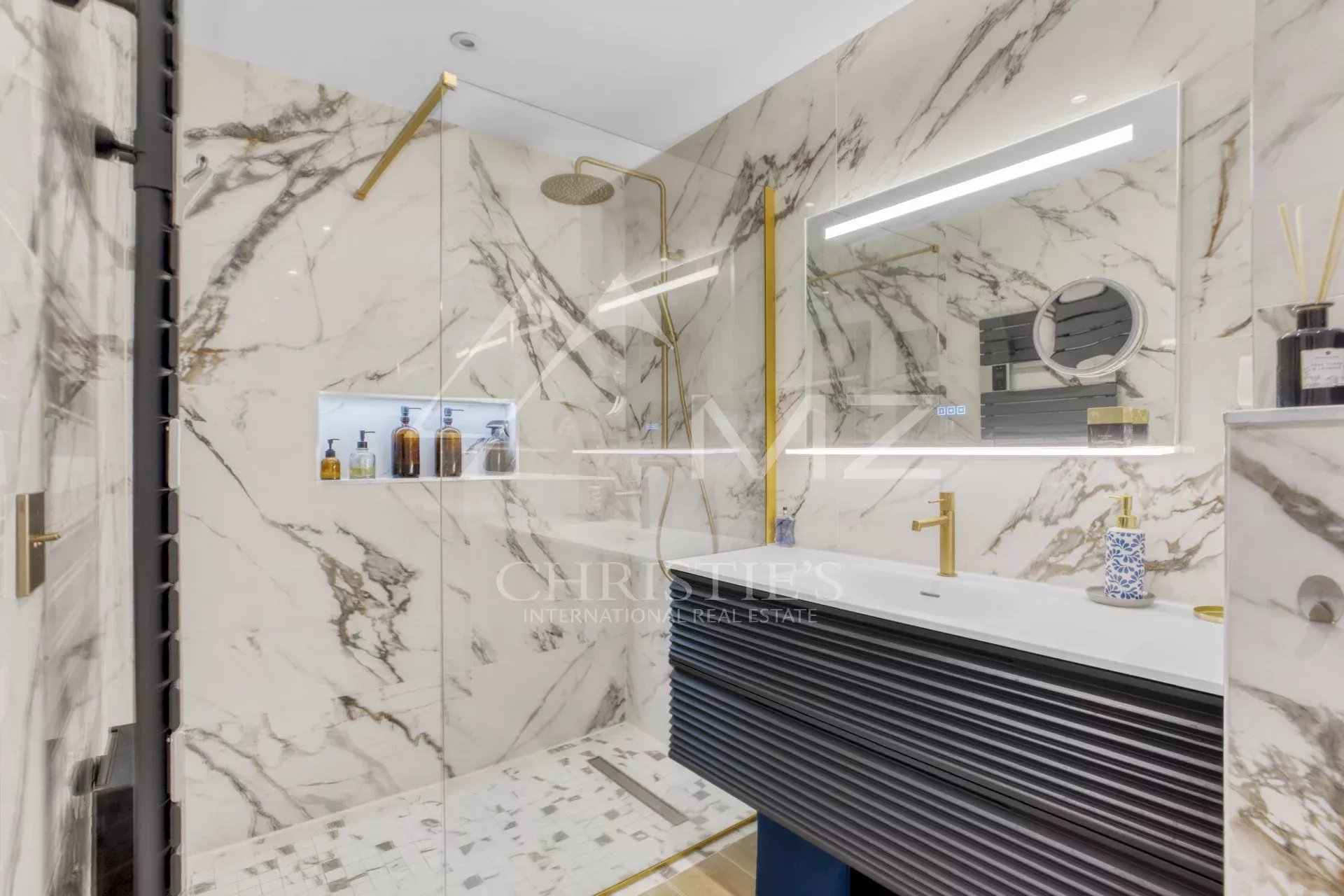Salle de bain moderne avec douche en verre et décor en marbre.