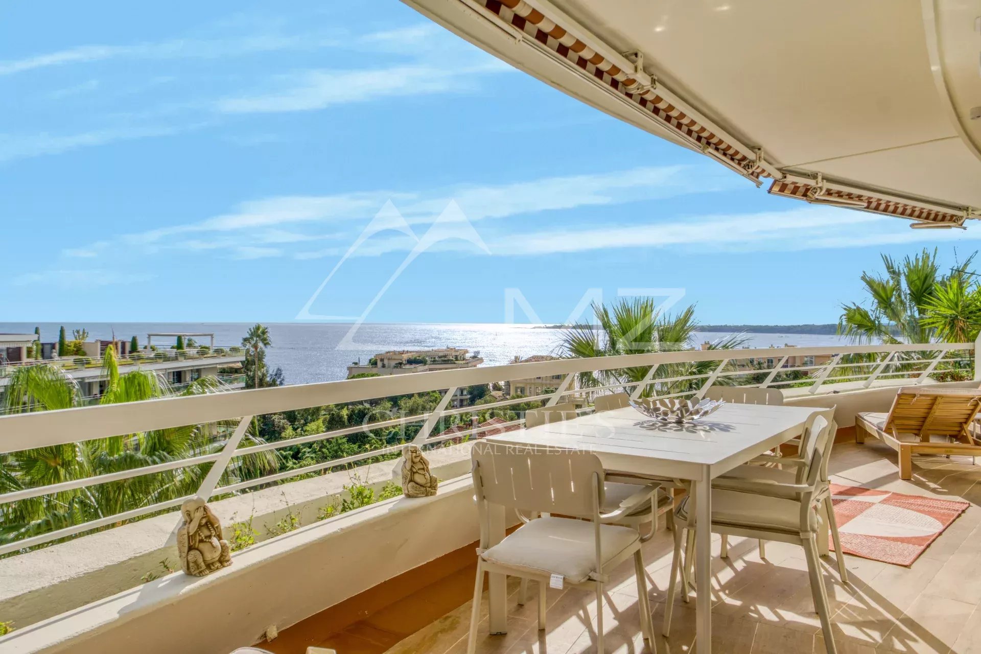 Terrasse d'un appartement avec vue panoramique sur la mer à Cannes, ensoleillée et décorée.