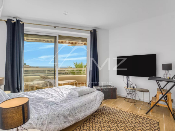 Chambre d'appartement avec vue sur la mer à Cannes, fenêtres ouvertes, décor moderne.