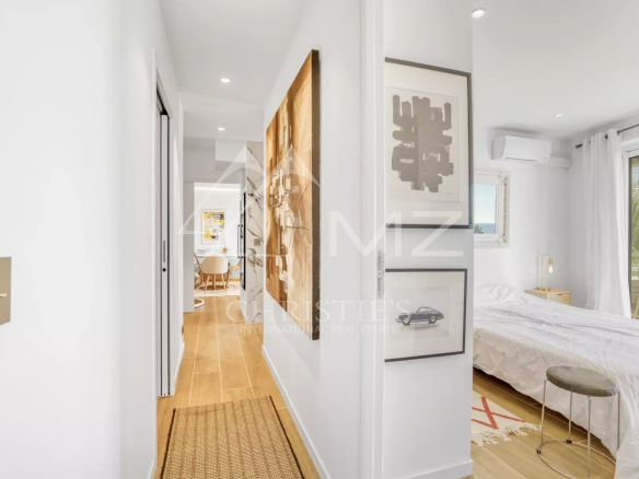 Intérieur d'un appartement à Cannes avec couloir menant à une chambre et un séjour lumineux.
