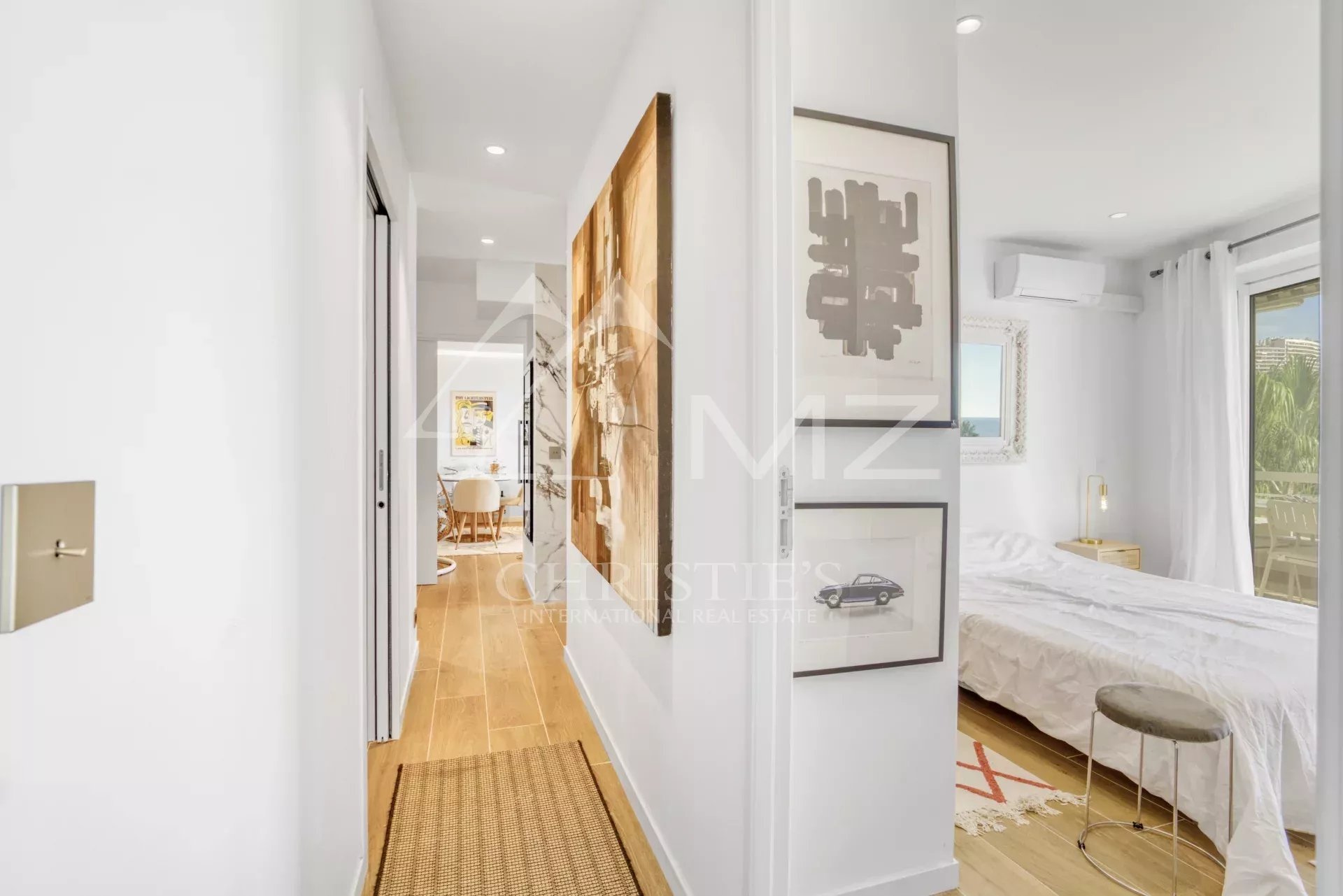 Intérieur d'un appartement à Cannes avec couloir menant à une chambre et un séjour lumineux.
