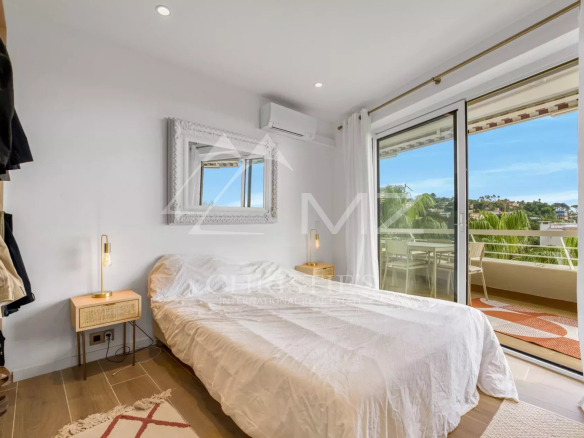 Chambre d'un appartement à Cannes avec vue sur la mer et accès à un balcon.