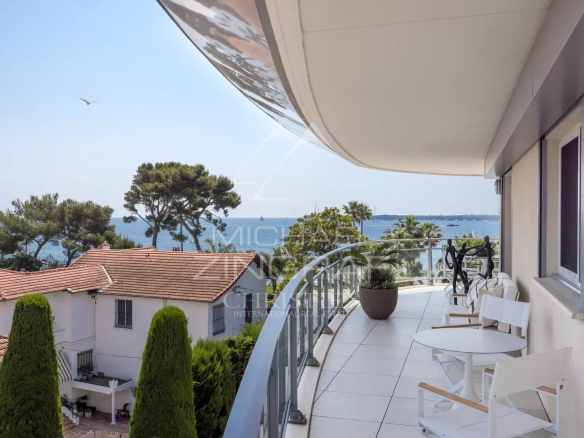 Balcony of an apartment in Cannes with views of the sea and surrounding trees.