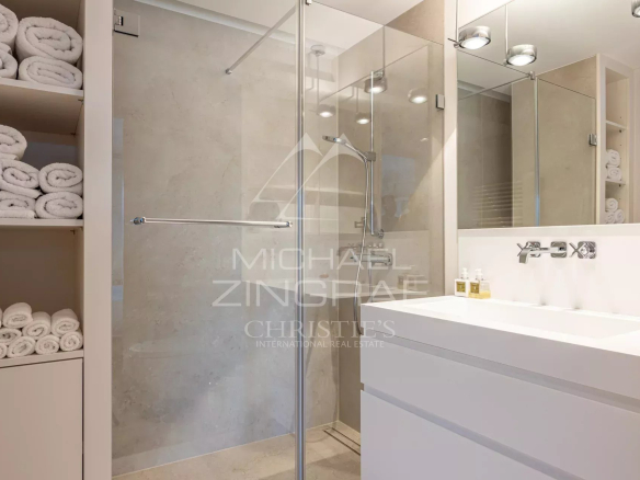 Modern bathroom with shower, sink and stacked white towels.