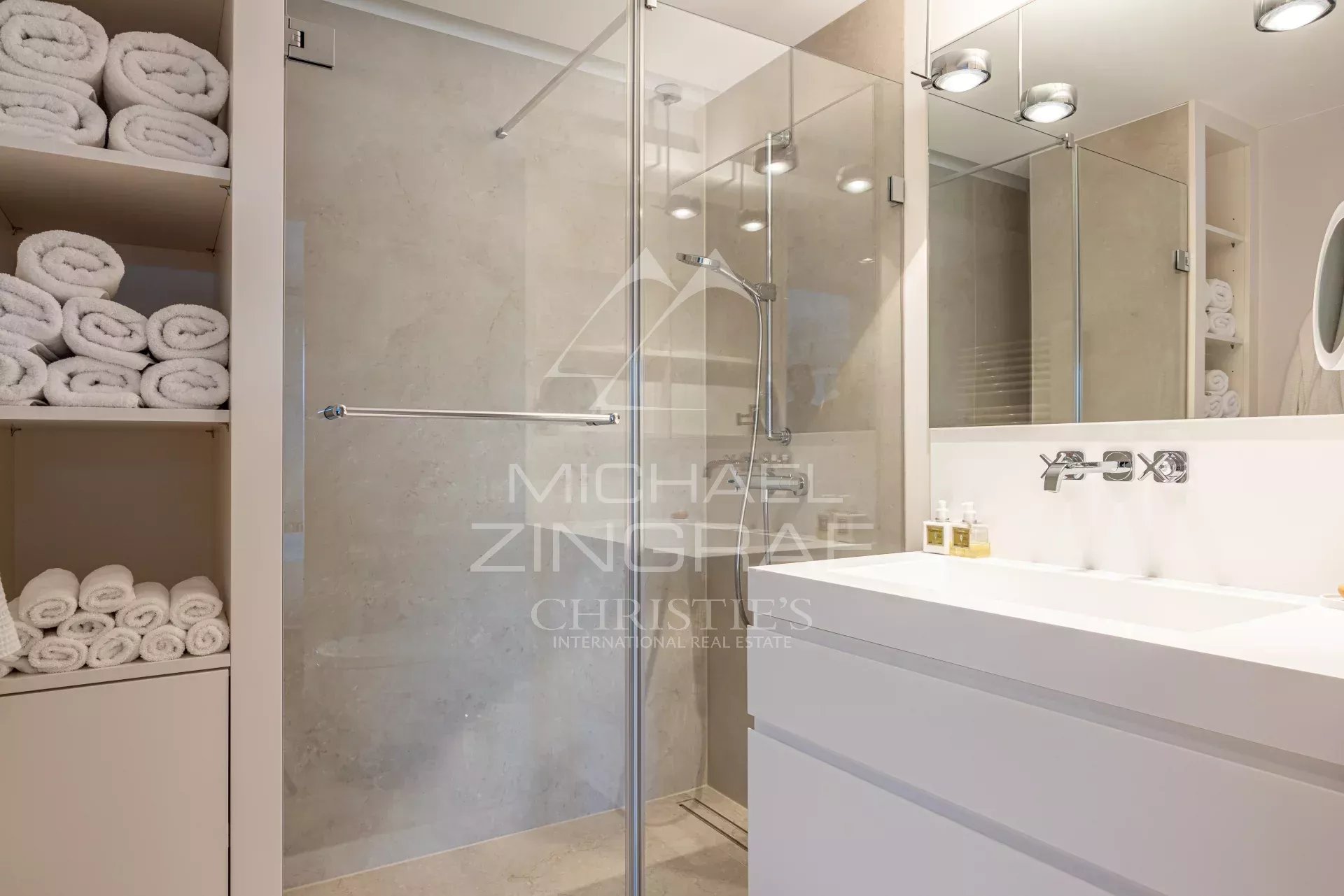 Bathroom of an apartment in Cannes Modern bathroom with shower, sink and stacked white towels.