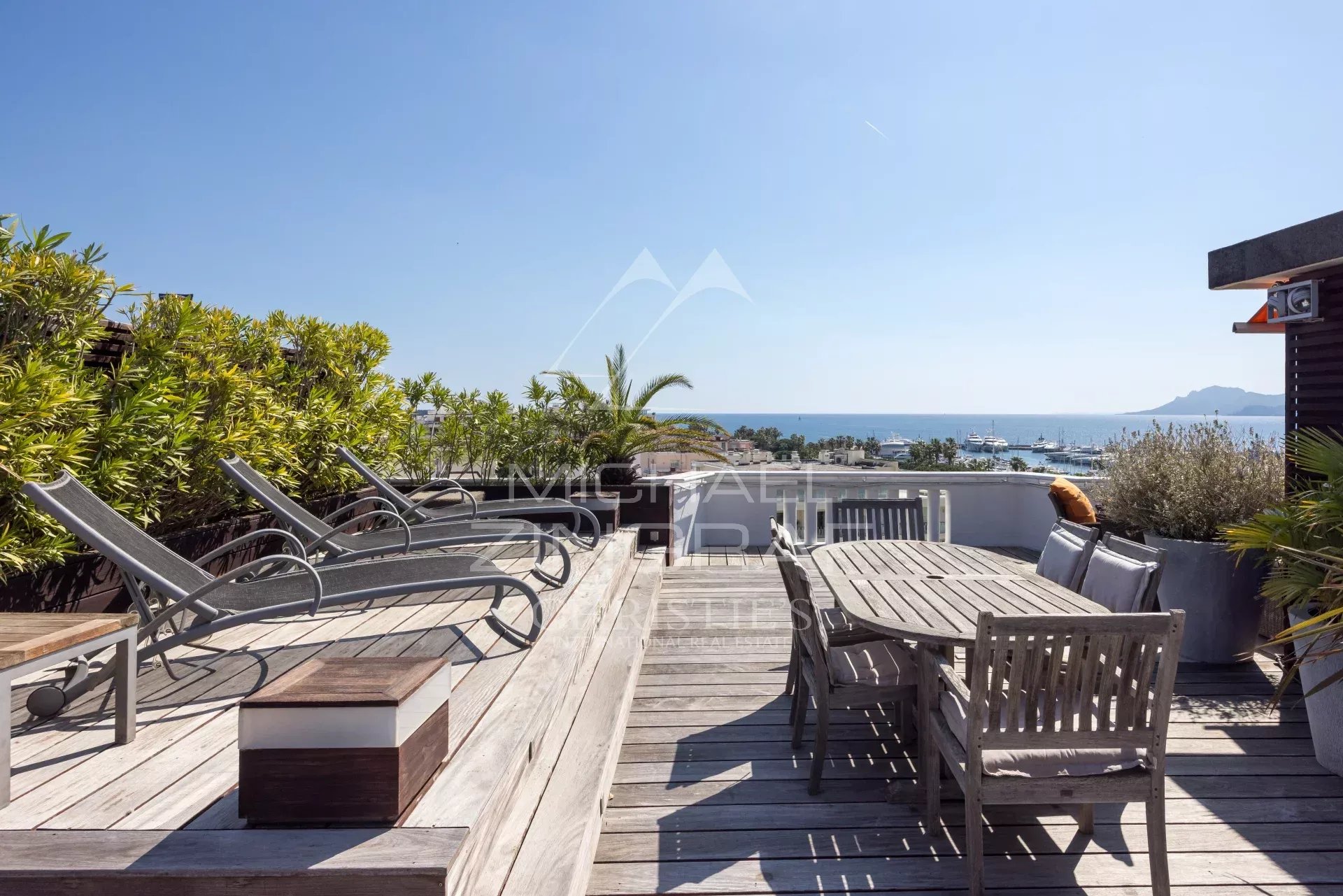 Penthouse with roof terrace in Cannes Wooden terrace with furniture and sea view in Cannes.