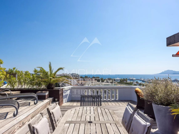 Wooden terrace with sea view in Cannes, outdoor furniture and plants.