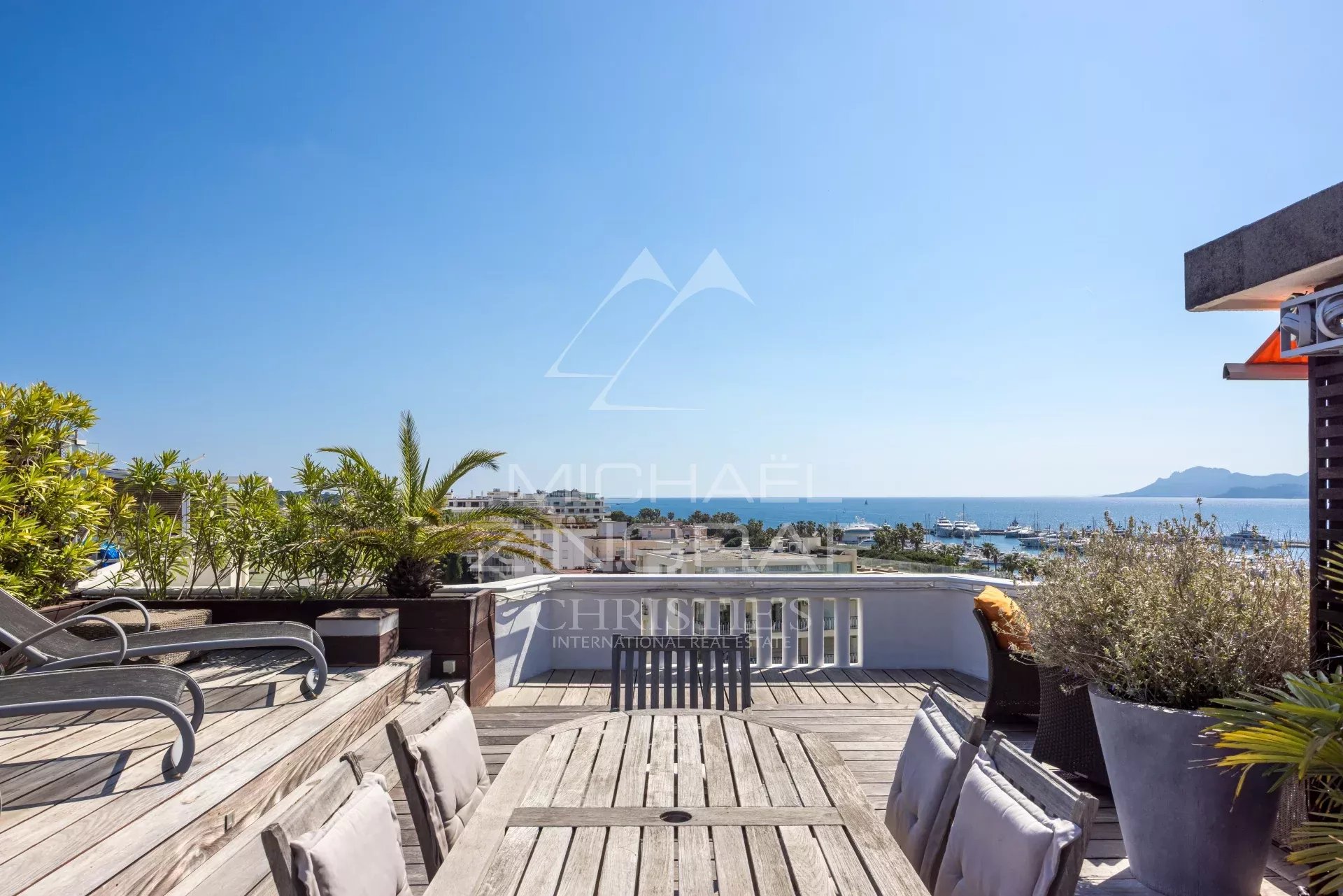 Penthouse with roof terrace in Cannes Wooden terrace with sea view in Cannes, outdoor furniture and plants.