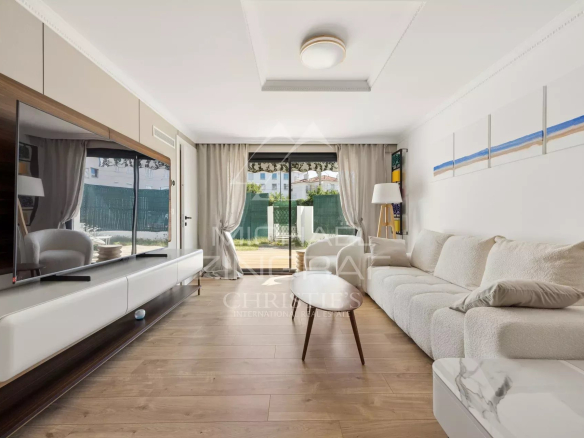 Salon d'un appartement moderne avec canapé et télévision, accès à une terrasse.