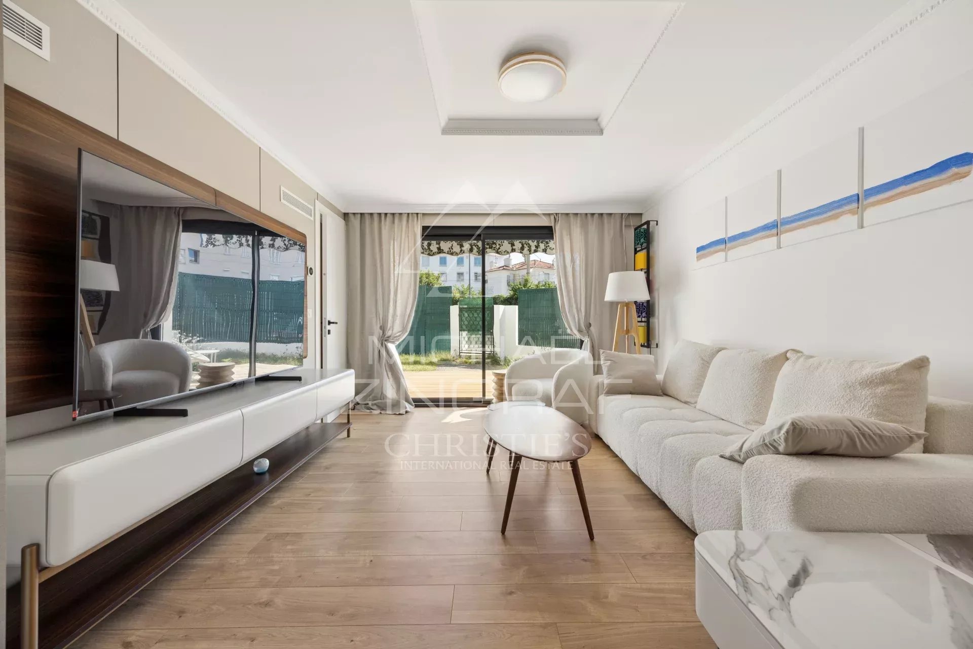 Salon d’appartement à Cannes Salon d'un appartement moderne avec canapé et télévision, accès à une terrasse.