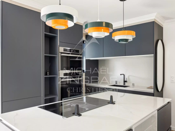 Cuisine moderne avec îlot central et éclairage design dans un appartement rénové.