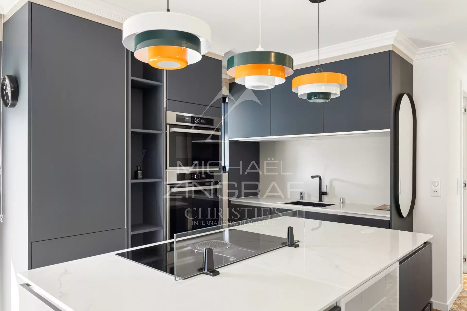 Cuisine d’un appartement à Cannes Cuisine moderne avec îlot central et éclairage design dans un appartement rénové.