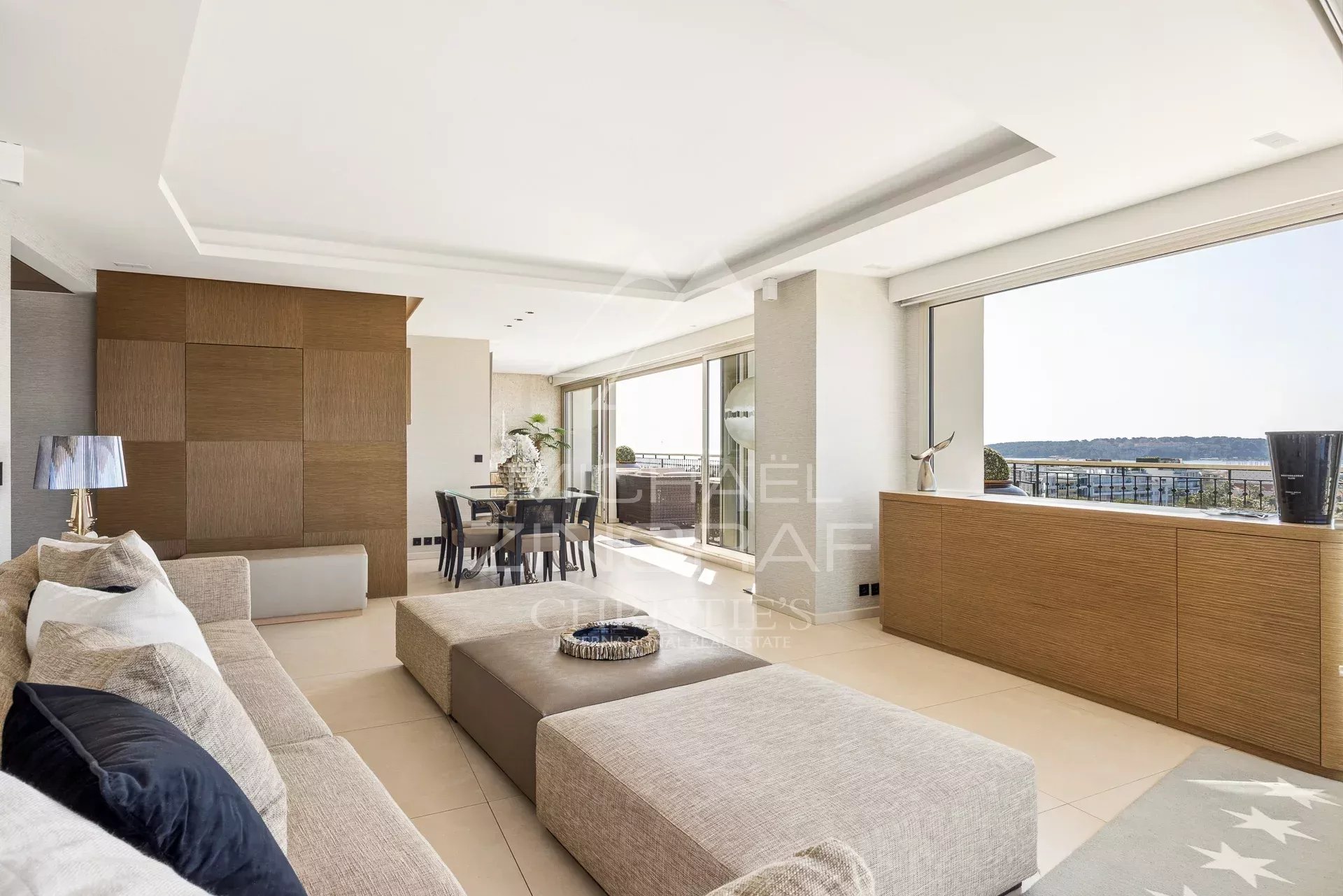 Intérieur d'un penthouse lumineux avec salon moderne et vue sur la mer.