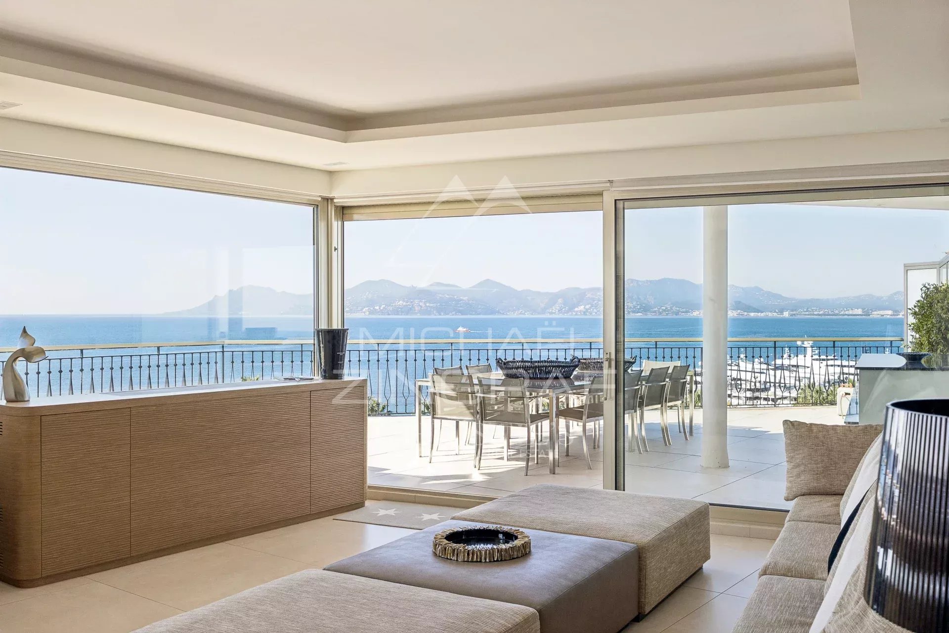 Intérieur d'un penthouse lumineux avec vue sur la mer à Cannes, terrasse panoramique visible.