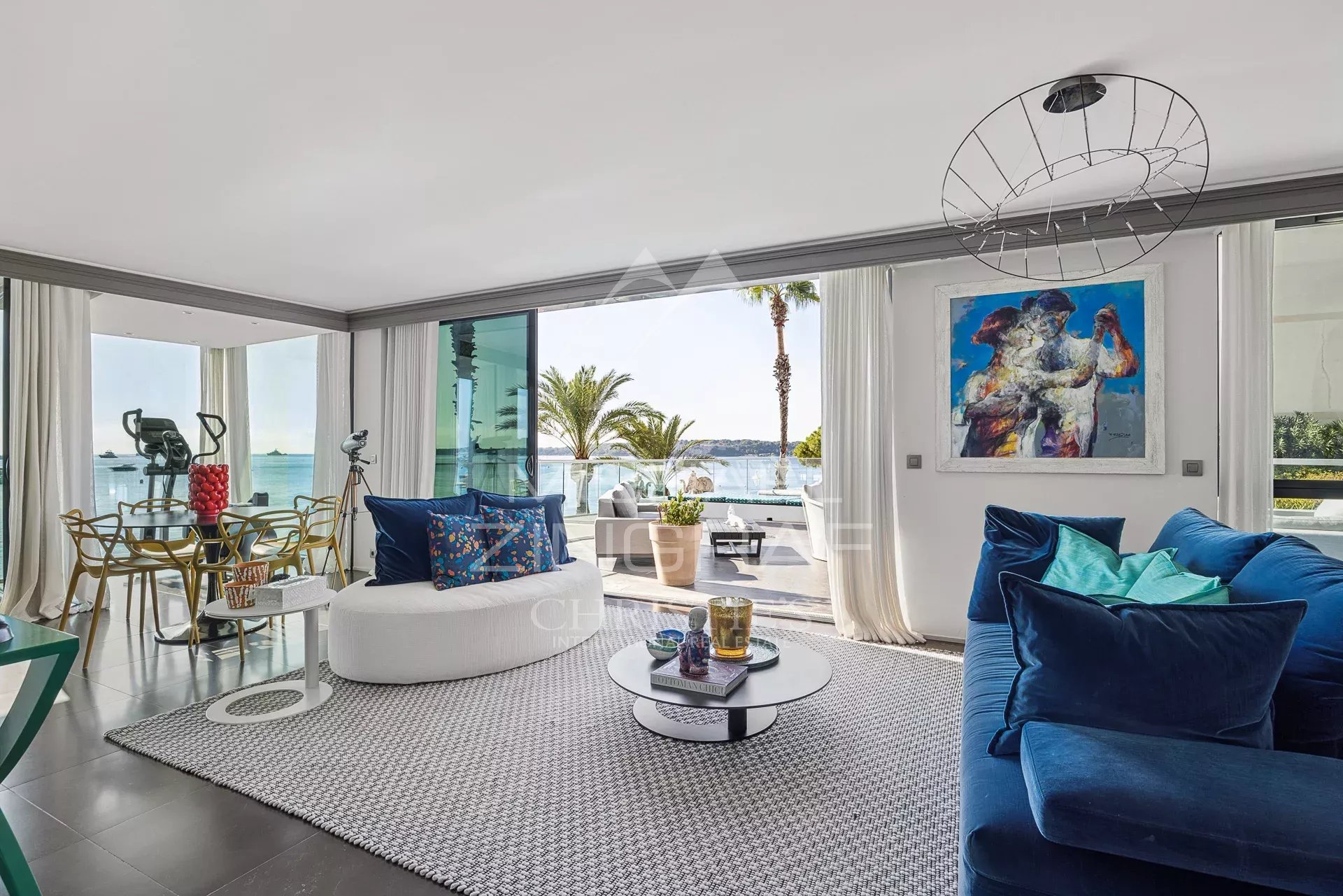 Intérieur d'un triplex moderne avec vue sur la mer, salon lumineux et mobilier contemporain.