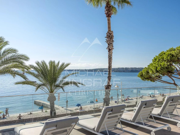 Vue sur la mer depuis une terrasse avec des transats et des palmiers à Cannes.