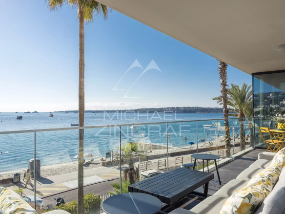 Vue panoramique sur la mer depuis une terrasse d'un triplex à Cannes, avec des palmiers et des bateaux au loin.