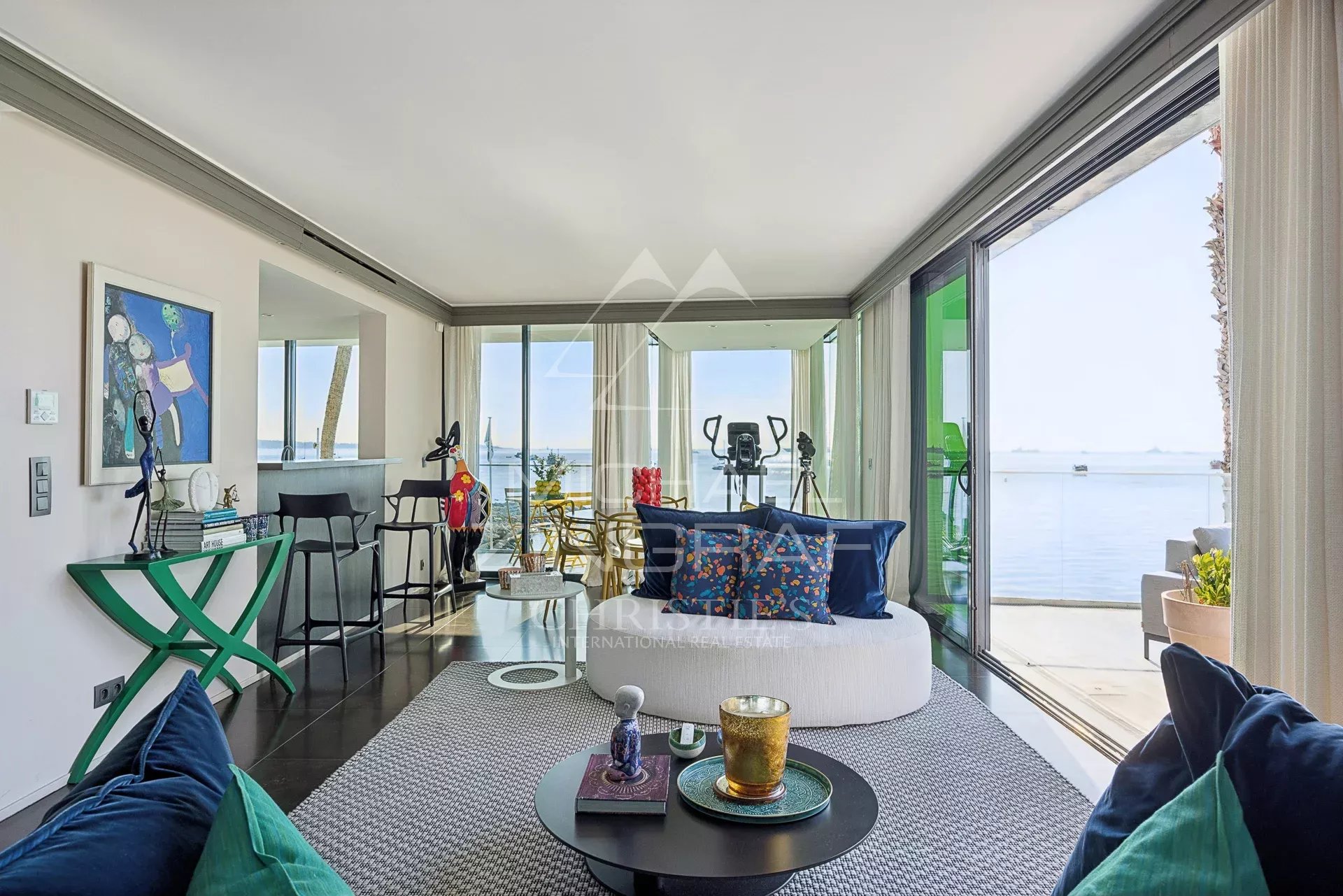 Intérieur d'un triplex moderne avec vue sur la mer à Cannes, comprenant un salon lumineux et des baies vitrées.