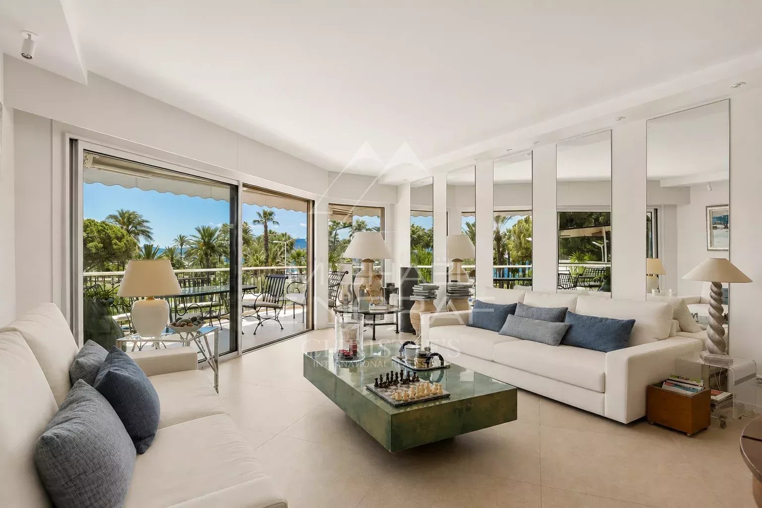 Salon d’un appartement à Cannes Salon lumineux d'un appartement moderne avec terrasse, vue sur la verdure et le port.