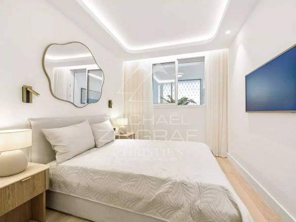 Chambre d'un appartement rénové avec lit double et décoration moderne à Cannes.