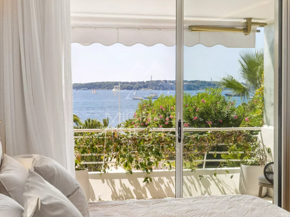 Vue depuis une chambre d'un appartement à Cannes avec balcon et mer en arrière-plan.