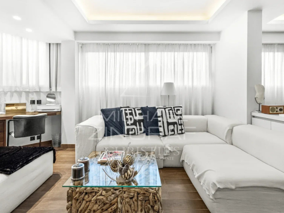 Intérieur d'un studio moderne et spacieux avec un canapé blanc et des rideaux clairs.
