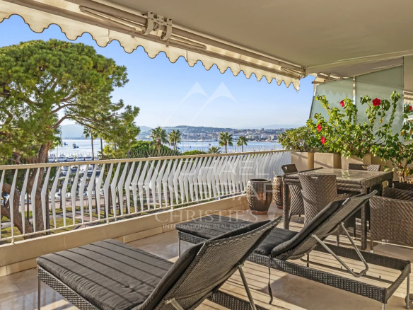 Terrasse d'un appartement à Cannes avec vue sur la mer et des chaises longues.
