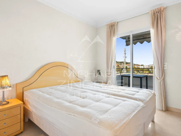 Chambre d'un appartement à Cannes avec lit et accès à un balcon.