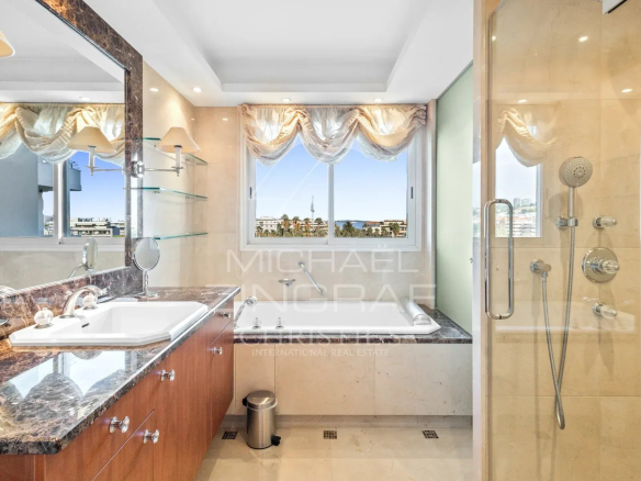 Salle de bain moderne avec baignoire et douche, vue sur la mer à Cannes.