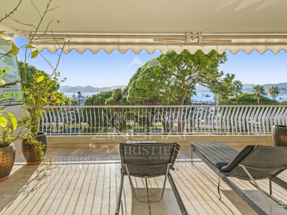 Terrasse d'un appartement à Cannes avec vue sur la mer et des chaises longues.