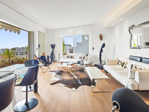Salon lumineux d'un appartement rénové à Cannes avec vue sur la mer, mobilier moderne et décoration élégante.