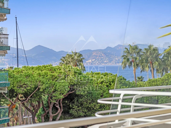 Vue depuis une terrasse d'un appartement à Cannes, avec mer et montagnes en arrière-plan.