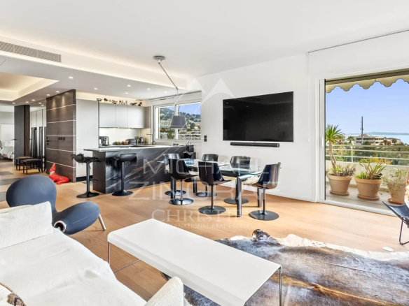 Intérieur d'un appartement moderne avec salon, cuisine ouverte et vue sur la mer à Cannes.