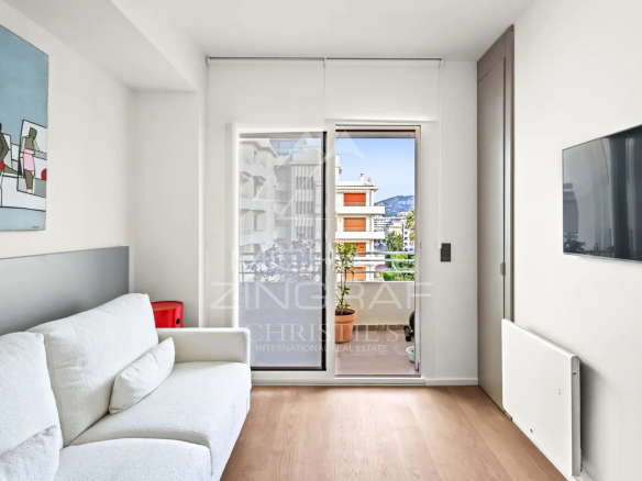 Intérieur d'un appartement rénové à Cannes avec un salon lumineux et accès à une terrasse.