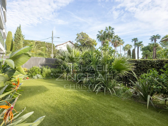 Jardin privatif d'un appartement à Palm Beach, Cannes, avec verdure et palmiers.