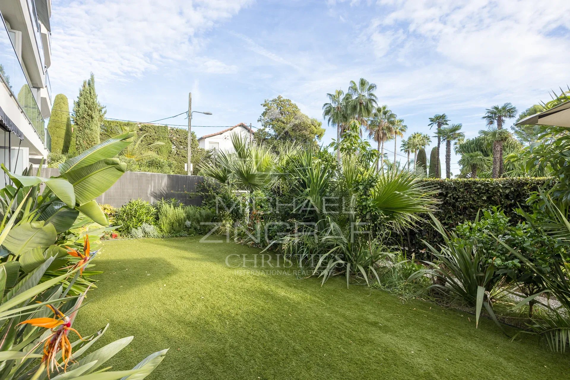 Jardin privatif d'un appartement à Palm Beach, Cannes, avec verdure et palmiers.