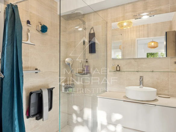 Salle de bain moderne avec douche en verre et lavabo sur meuble.