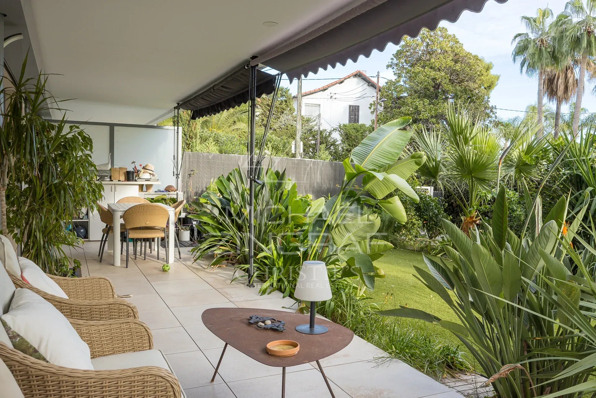 Terrasse d'un appartement avec jardin privatif à Cannes, entourée de plantes tropicales.