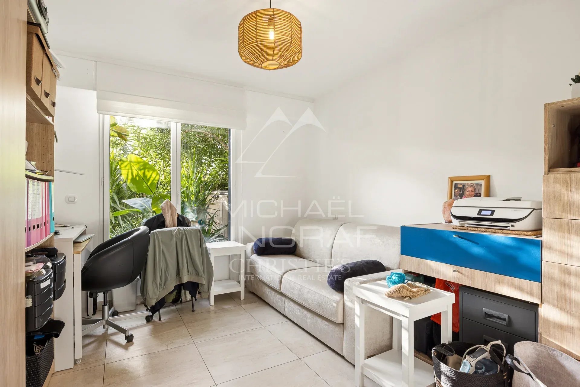 Intérieur d'un appartement avec un coin salon et une fenêtre donnant sur un jardin.
