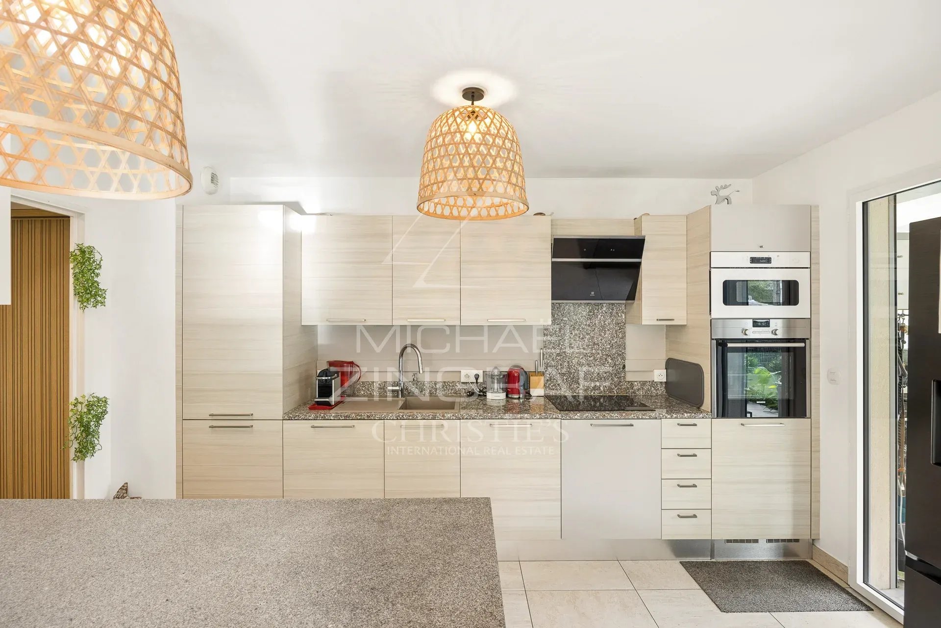 Cuisine moderne d'un appartement à Cannes avec meubles clairs et équipements intégrés.