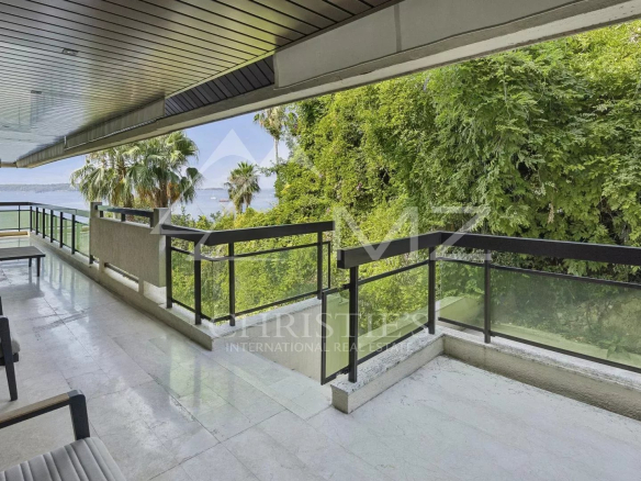 Terrasse d'un appartement contemporain avec vue sur la mer à Cannes, entourée de verdure.