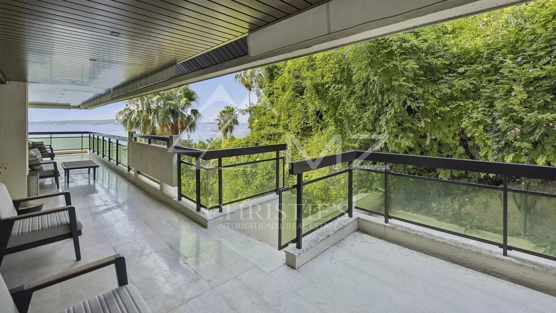 Terrasse d'un appartement contemporain avec vue sur la mer à Cannes, entourée de verdure.