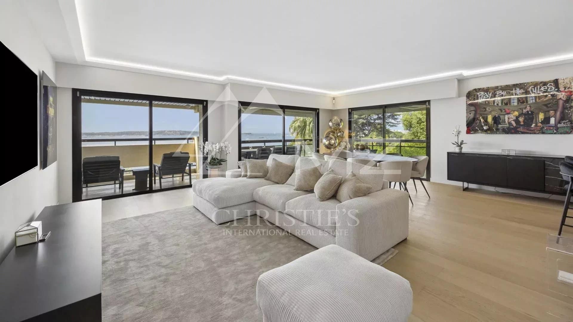 Intérieur d'un appartement contemporain avec vue sur la mer à Cannes, salon lumineux et terrasse.