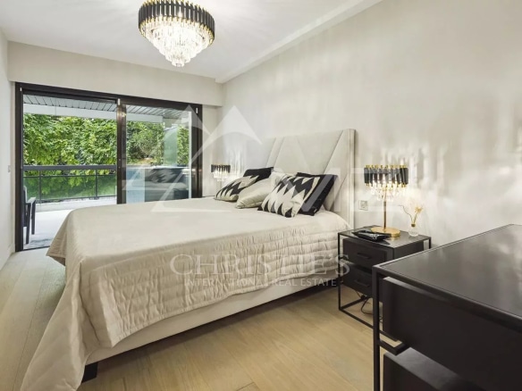 Chambre d'un appartement contemporain à Cannes avec lit double et accès à un balcon.