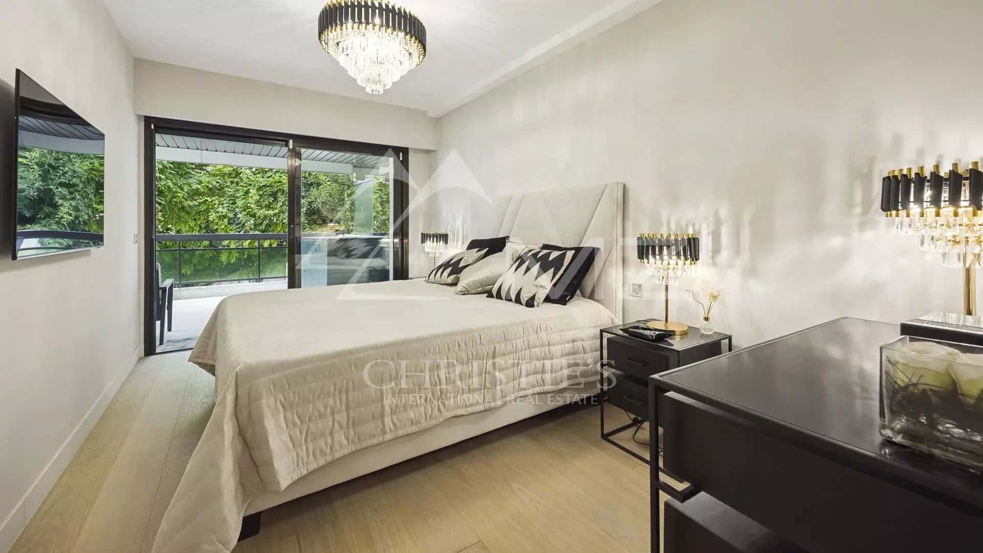 Chambre d'un appartement contemporain à Cannes avec lit double et accès à un balcon.