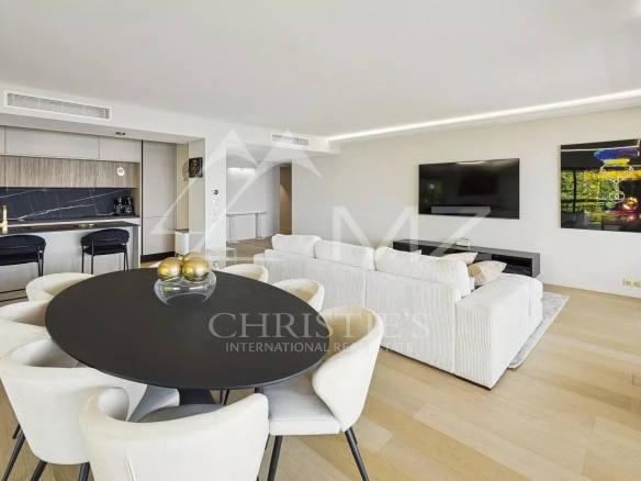 Intérieur d'un appartement contemporain avec salon lumineux, cuisine ouverte et vue sur la mer.