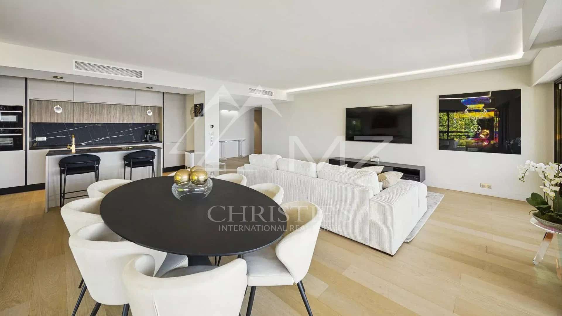 Intérieur d'un appartement contemporain avec salon lumineux, cuisine ouverte et vue sur la mer.